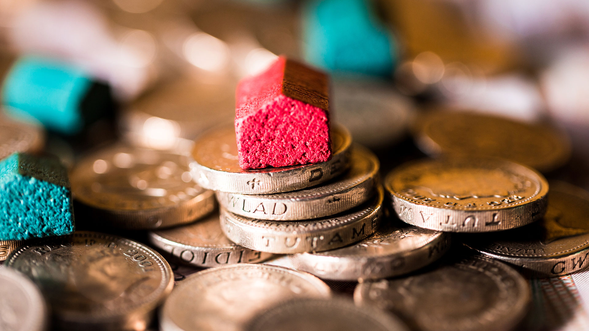 a pile of pound coins and small wooden house-shaped blocks. poverty uk