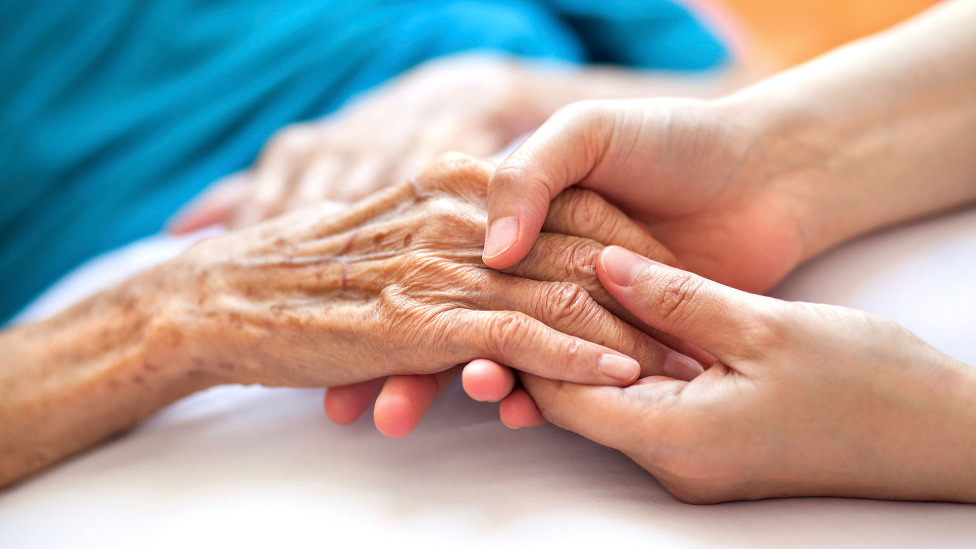 Nurse holding old woman's hand