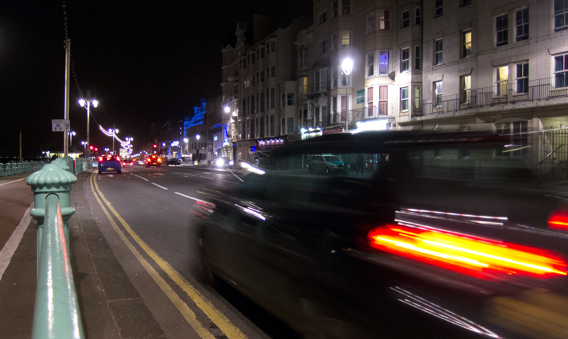 A car speeds along the seafront road in Brighton at night