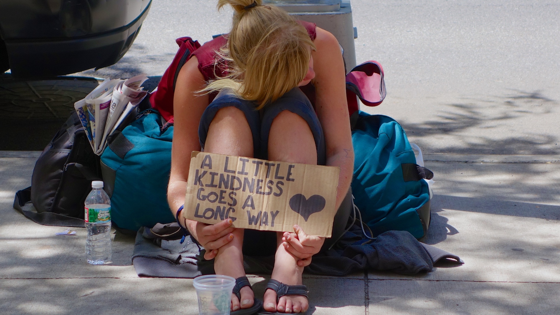 A woman holds a sign saying a little kindness goes a long way