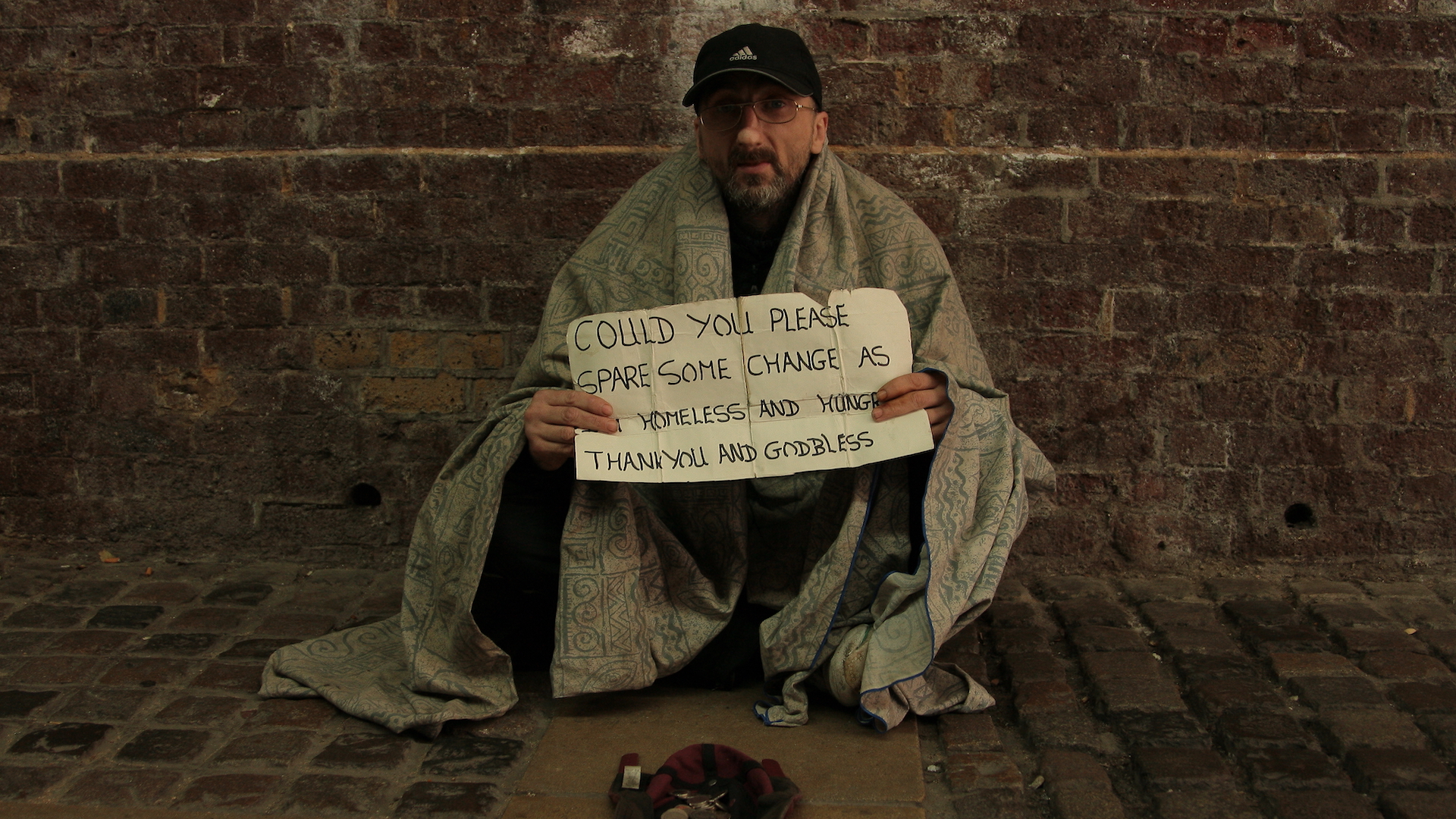 Homeless man holds a sign saying hungry and homeless
