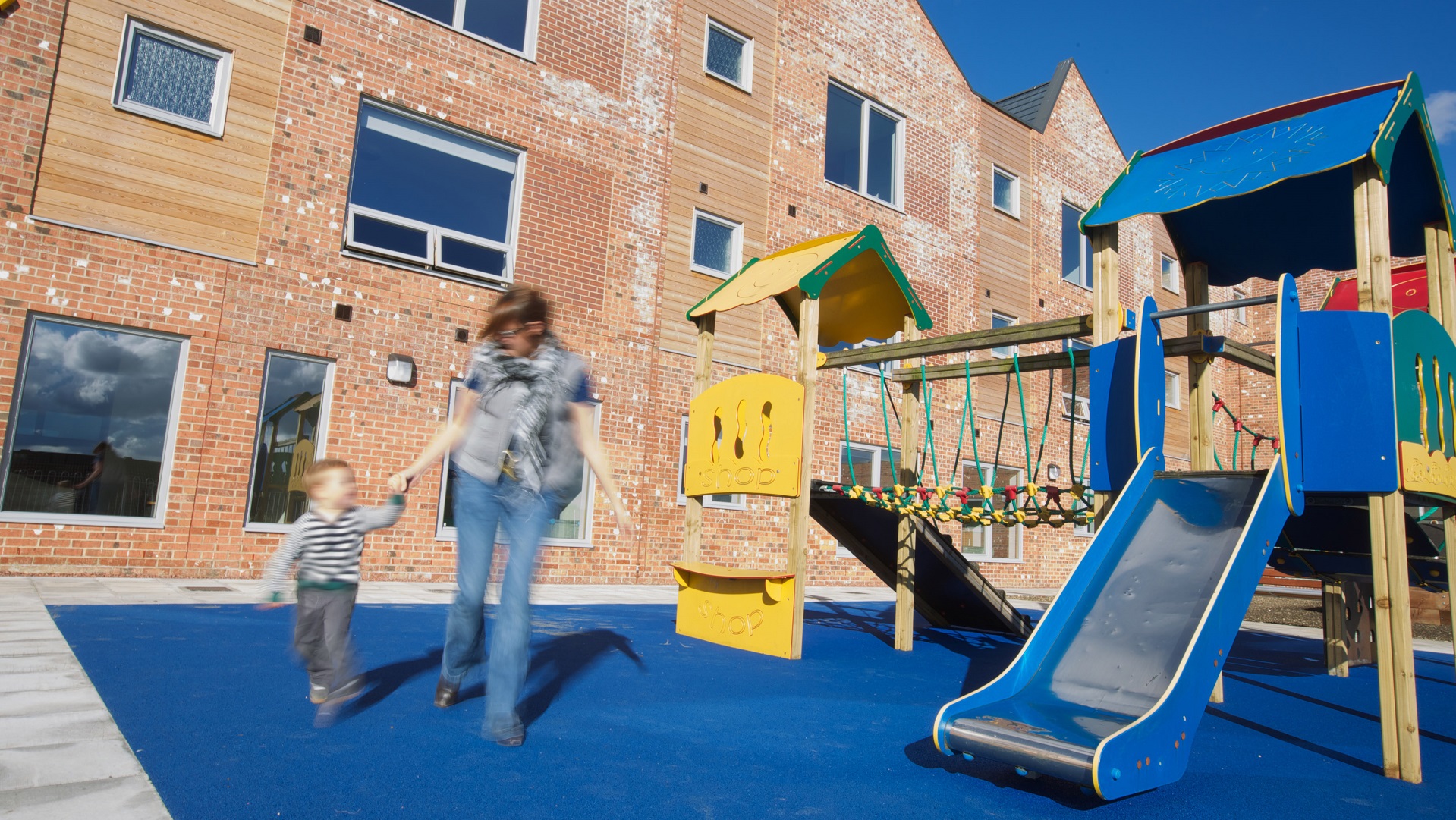 A resident and child enjoying the playground outside Cherry Tree View in Newcastle
