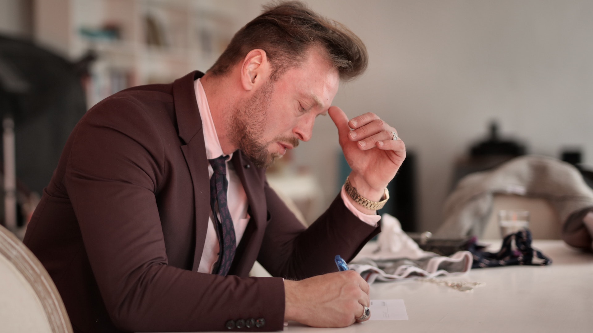 A man in a suit sits at a desk, pen in hand, worrying about redundancy rights