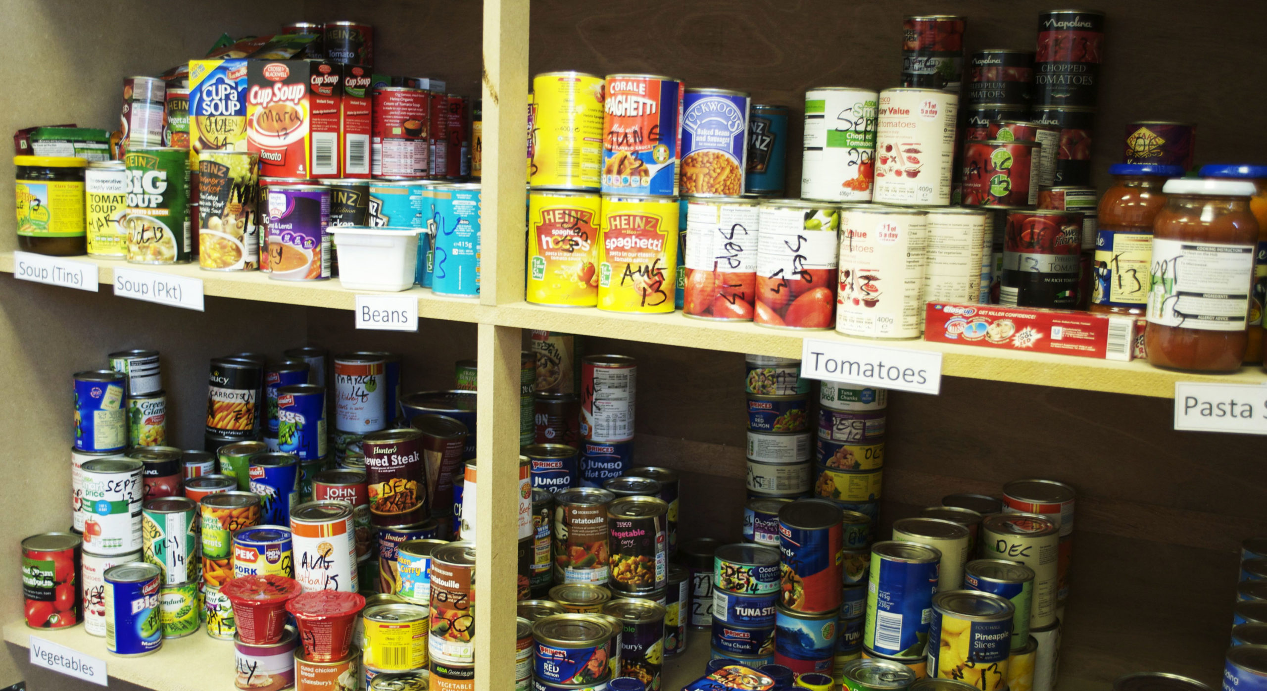 Foodbank shelves show a number of tins of food and packaging