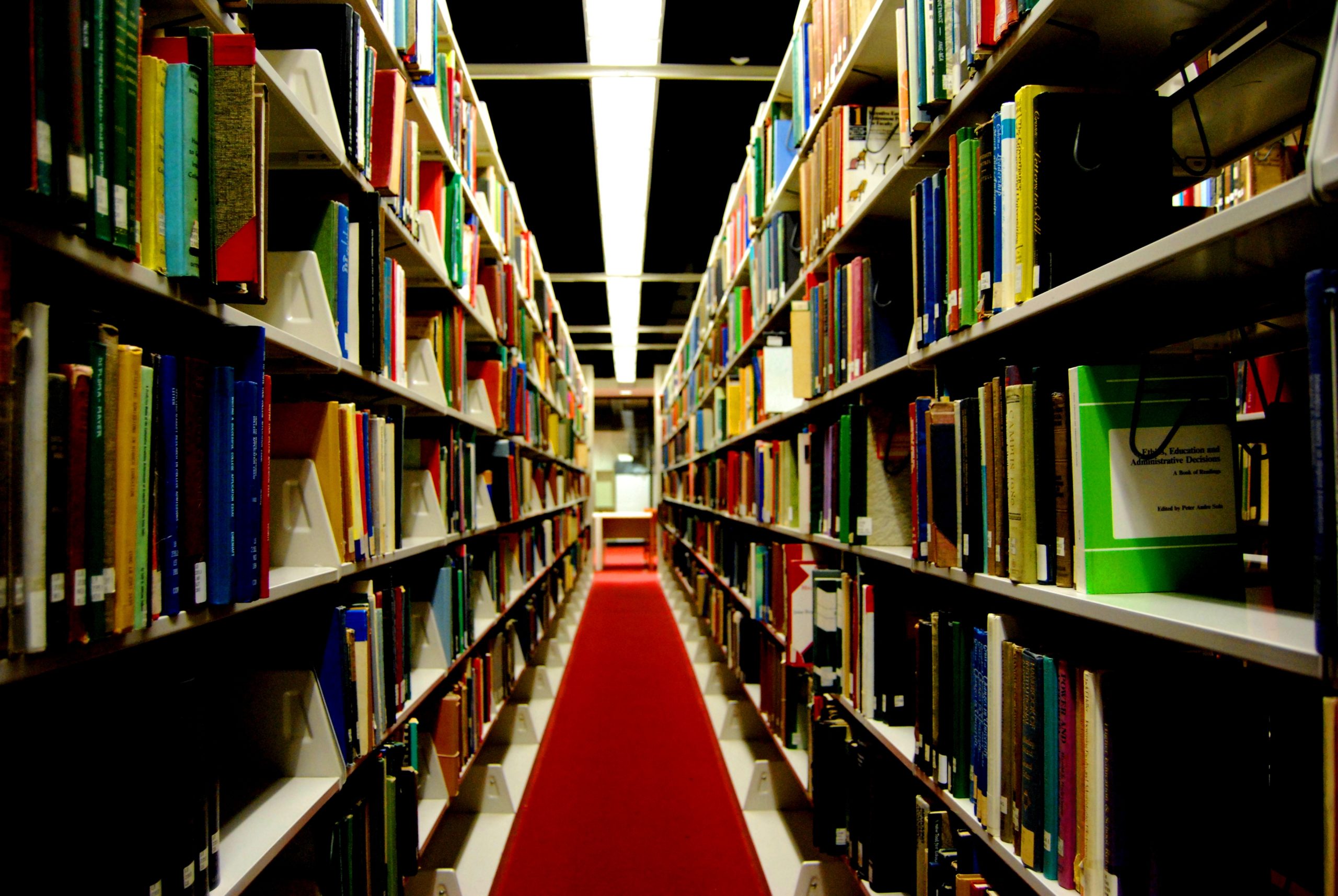 A long library stack shows rows of books on both left and right.