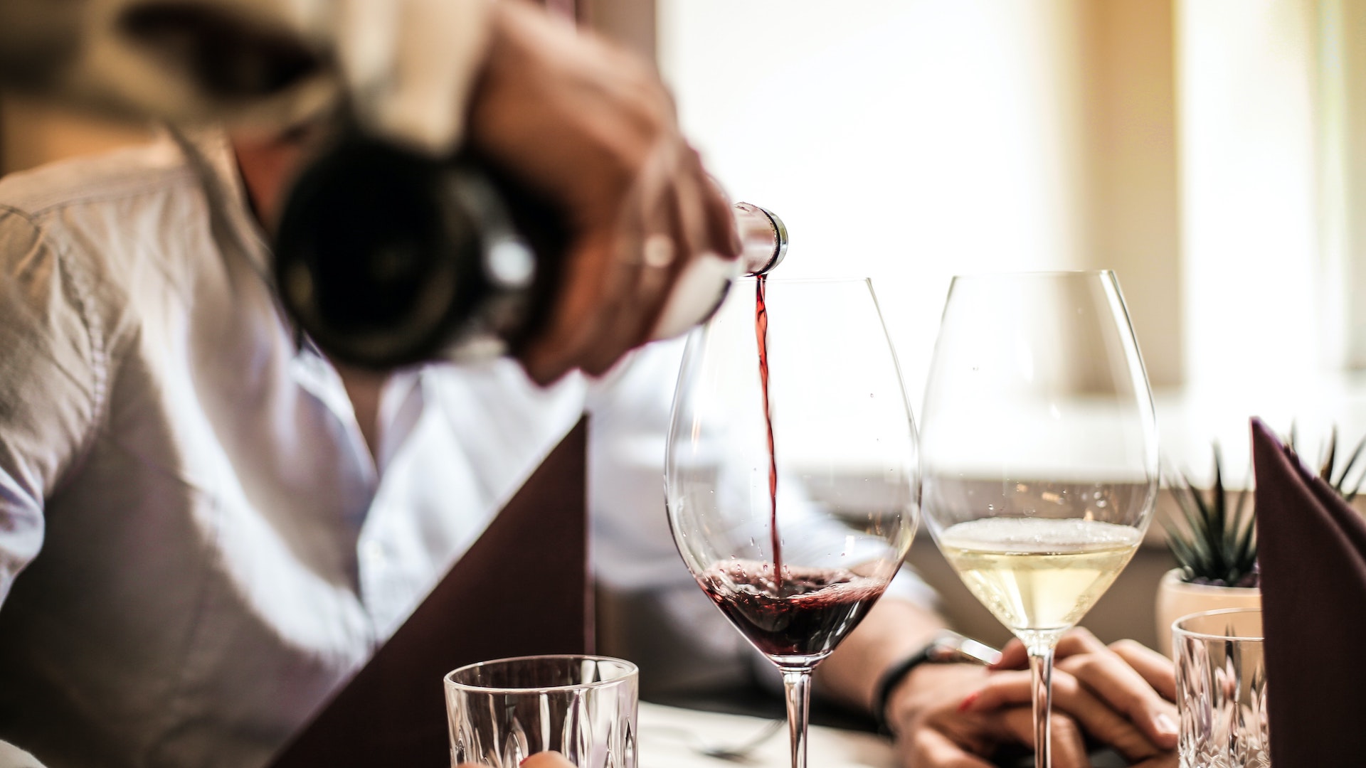 A waiter pours red wine into a glass. Restaurants must now give all tips to staff.