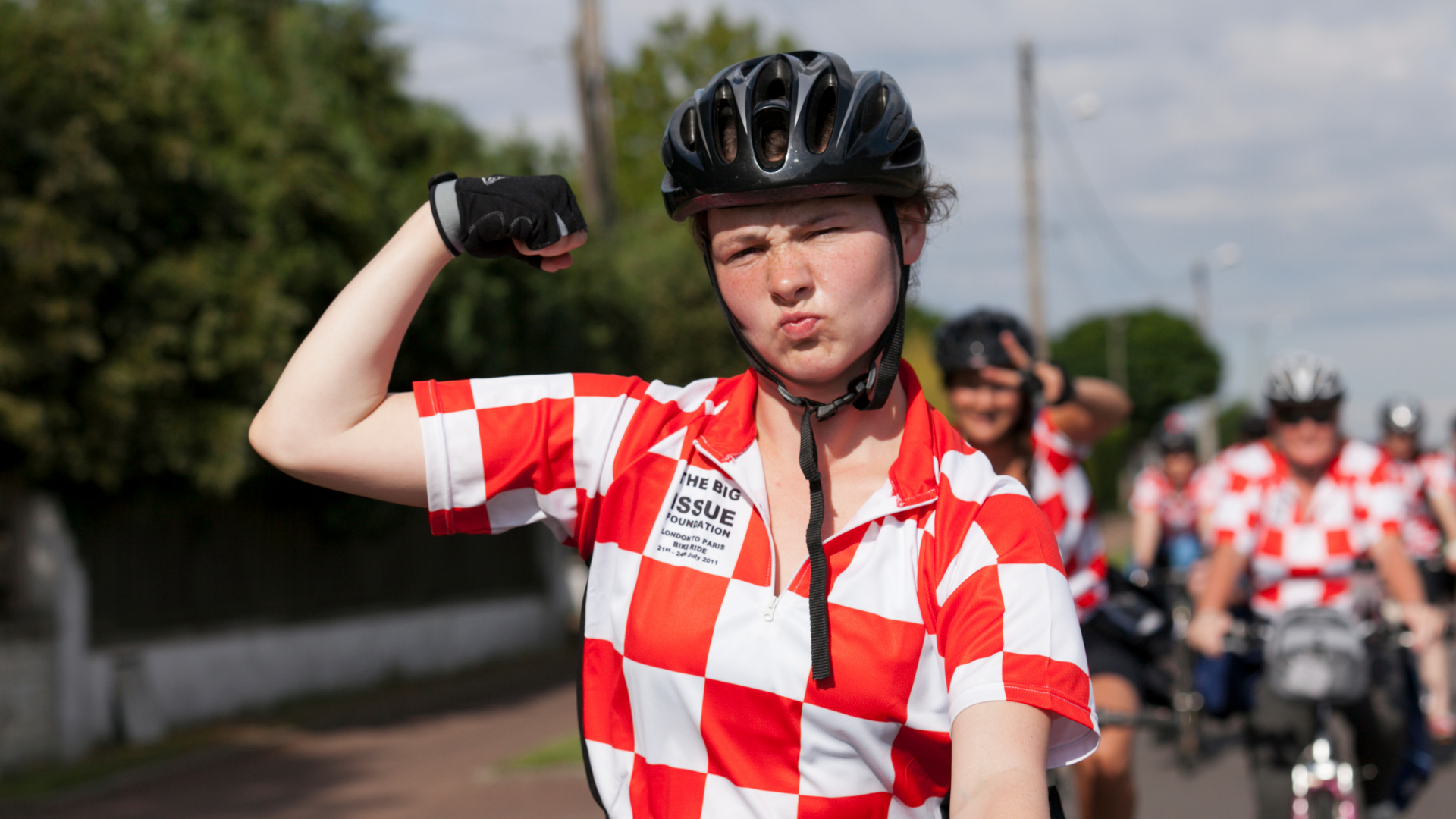 Women in Big Issue Foundation cycling jersey and helmet making a strong pose