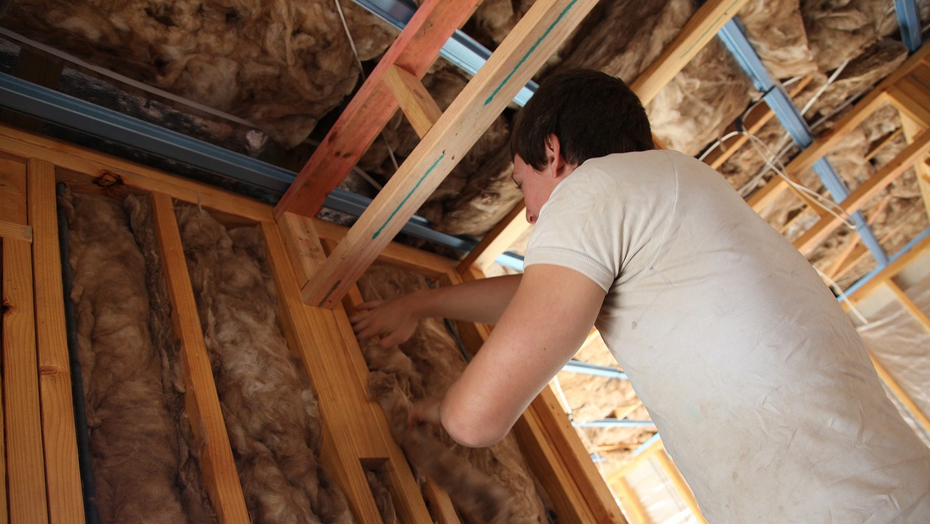 A man fitting insulation into a house.