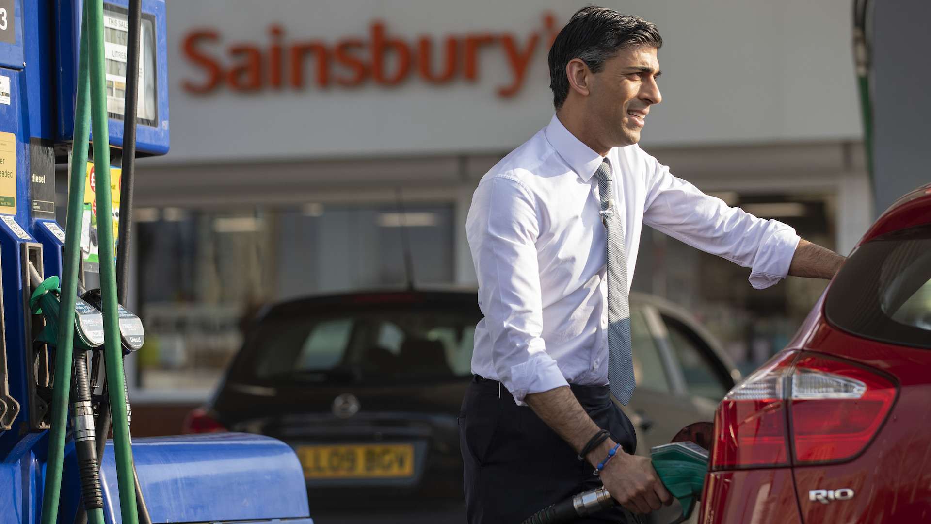 Rishi Sunak posing in front of a sainsbury's, filling an aide's car with petrol