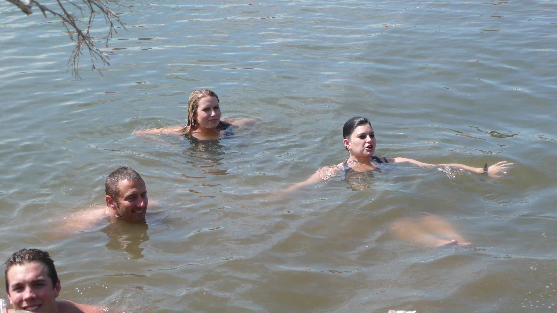 Four people swim in brown, murky river water