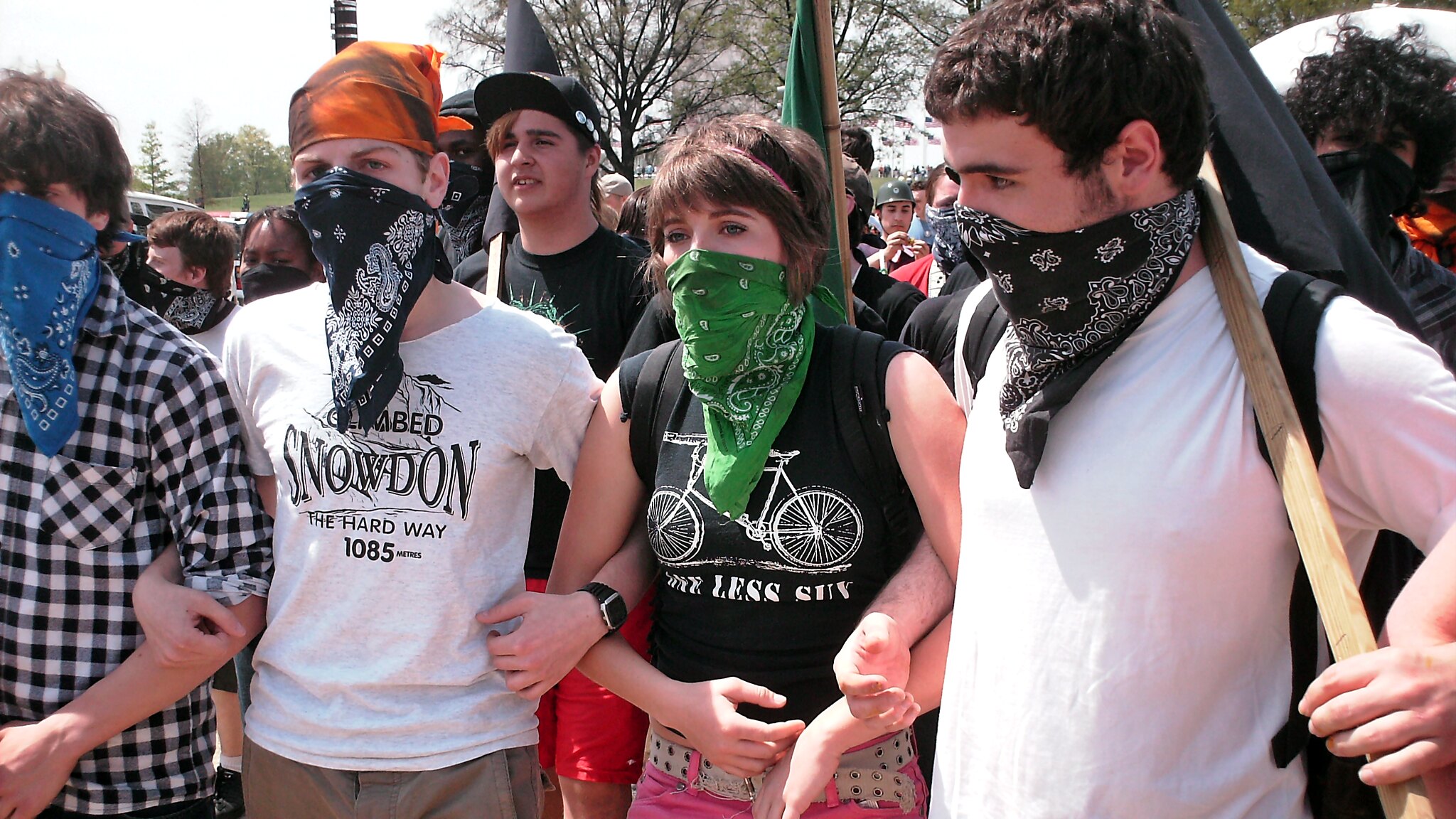 A group of masked demonstrators marches with arms locked at a demonstration on April 19, 2008 in Washington, DC