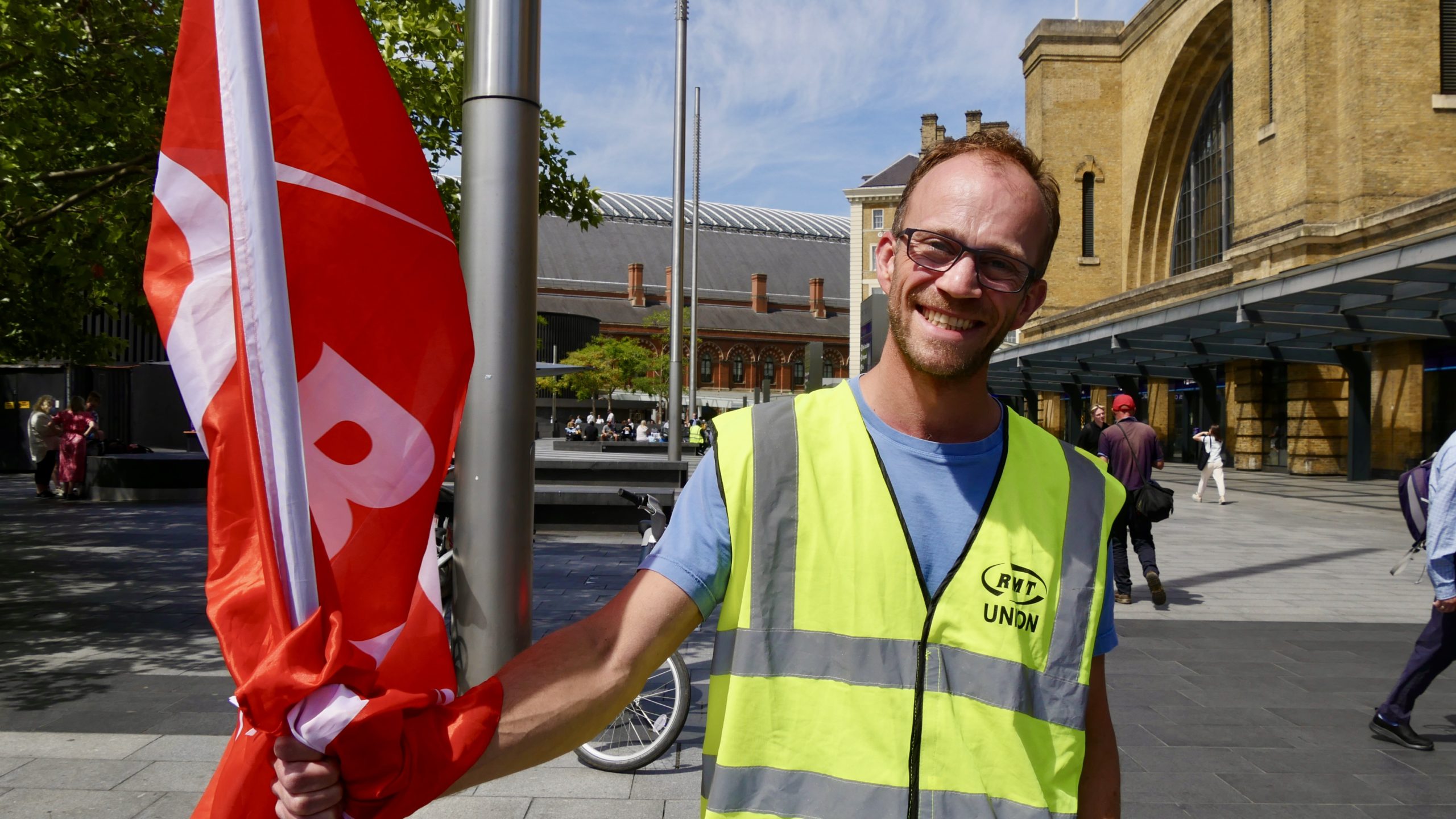 Union rail worker Matthew Lee holds a flag on the picket line outside King's Cross station