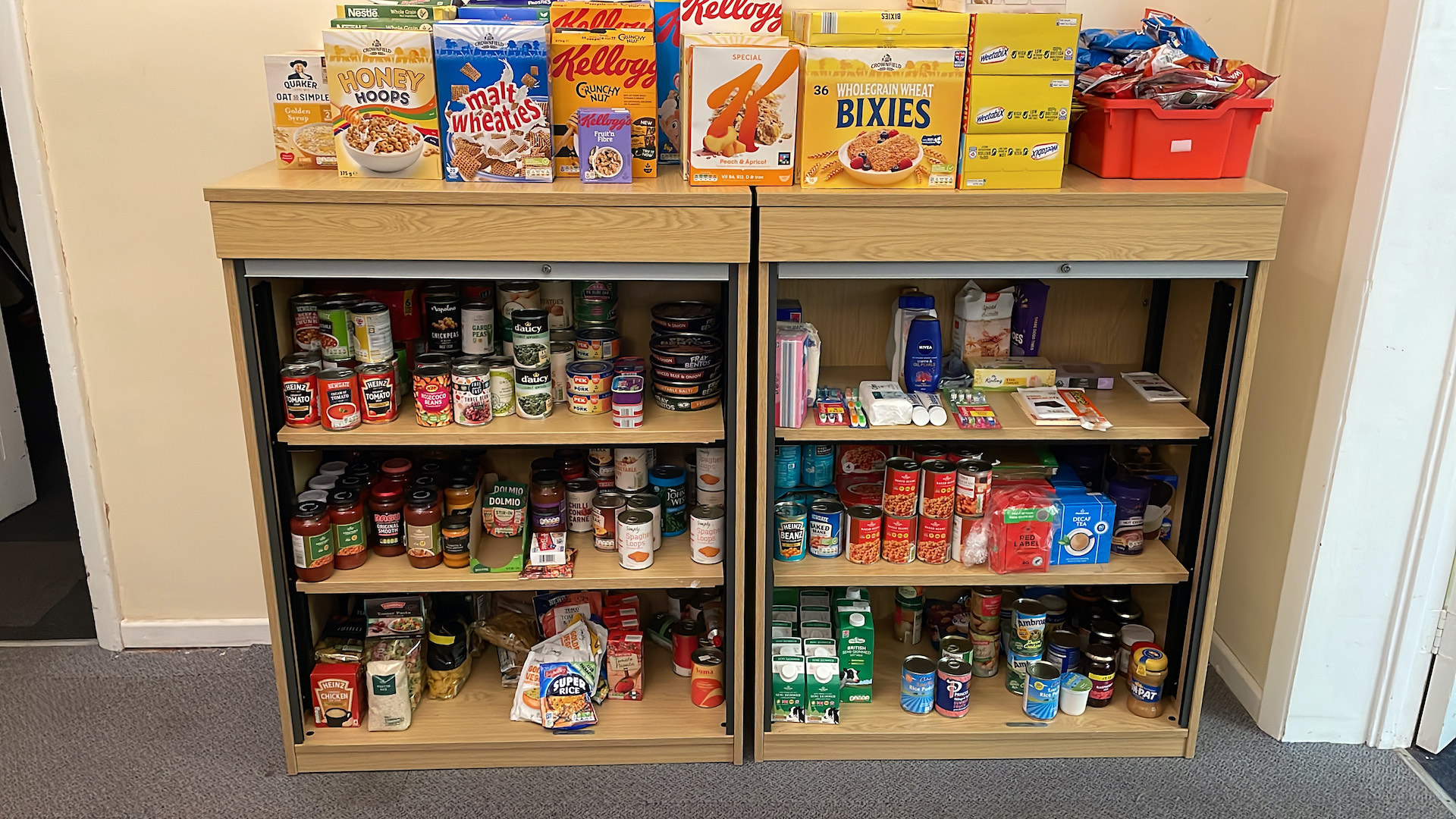 Cereal and cans of food sit in a low cupboard