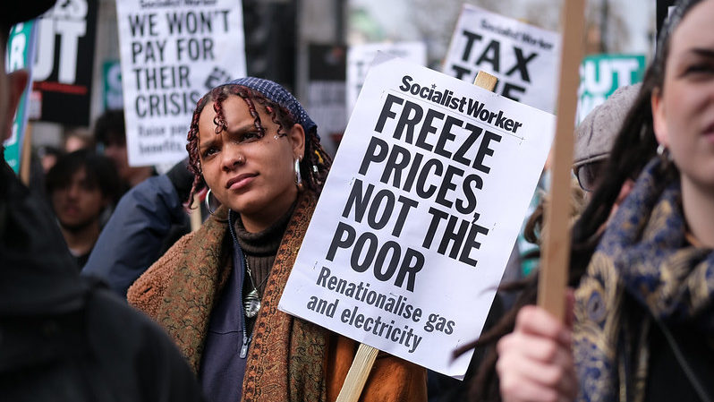 A protester with a placard reading: "Freeze prices not the poor".