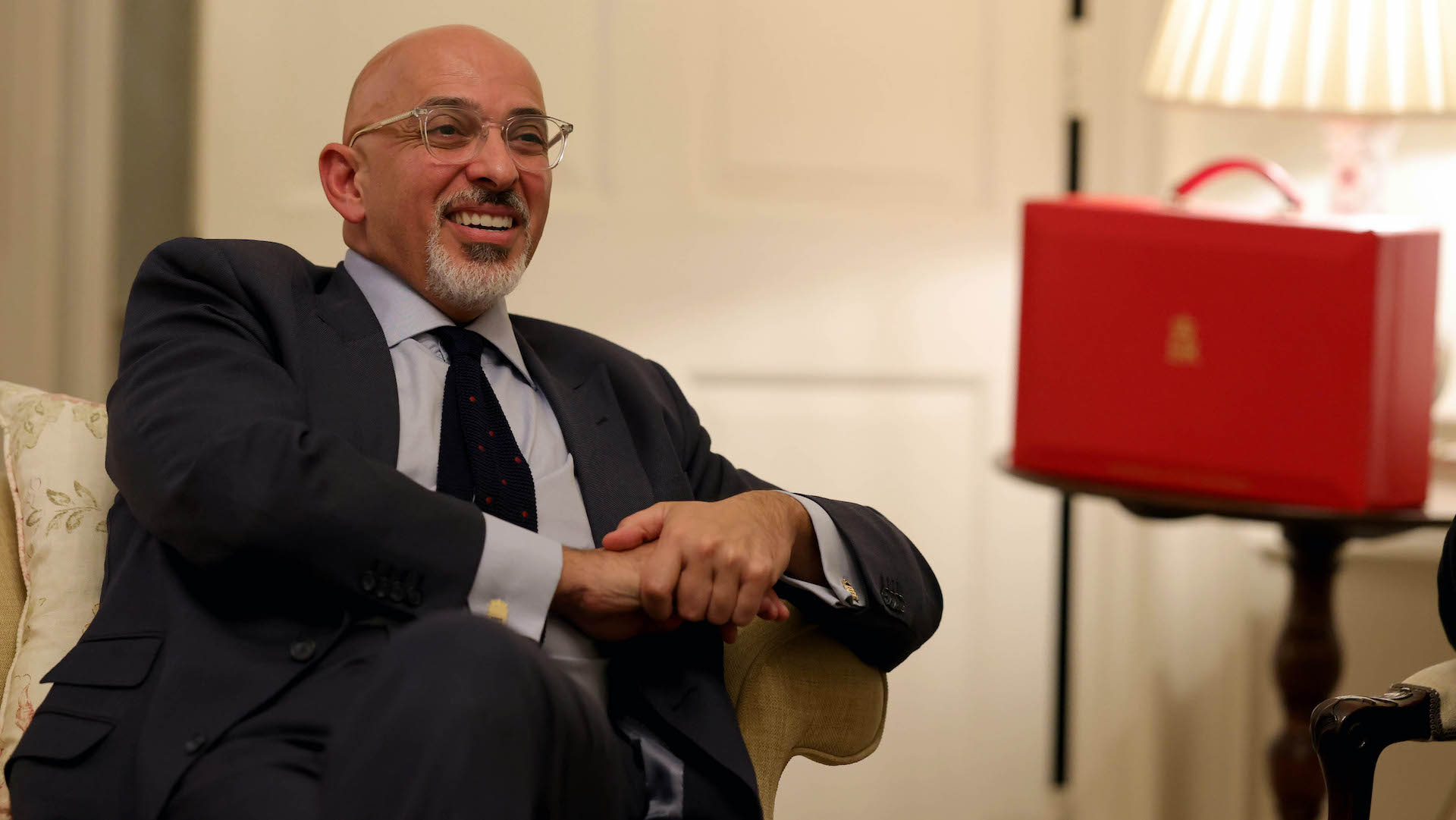 Nadhim Zahawi relaxes in a suit on a chair next to the chancellor's famous red dispatch box