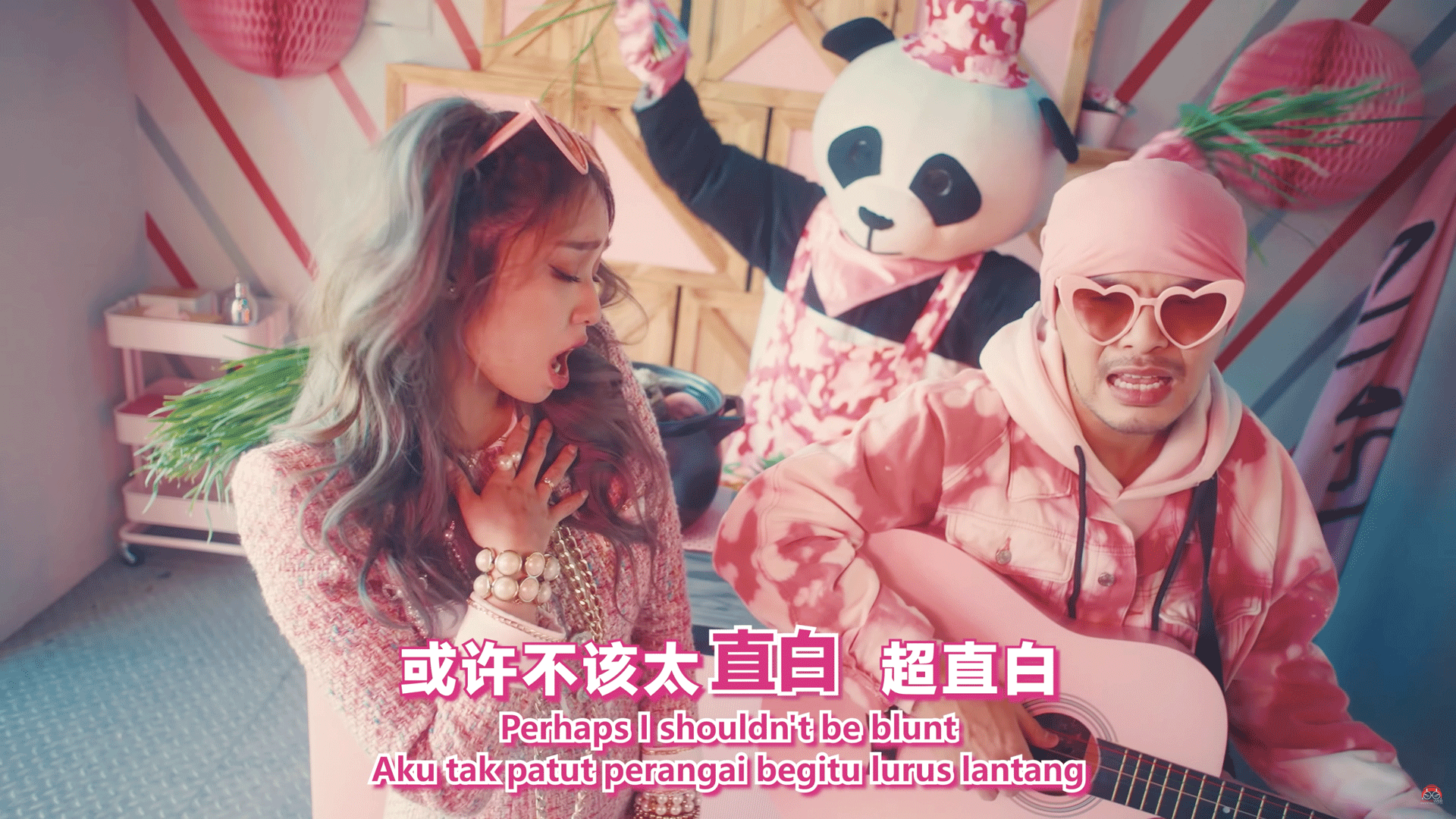 Namewee and Kimberley Chen sit at a pink table with a dancing panda bear behind them