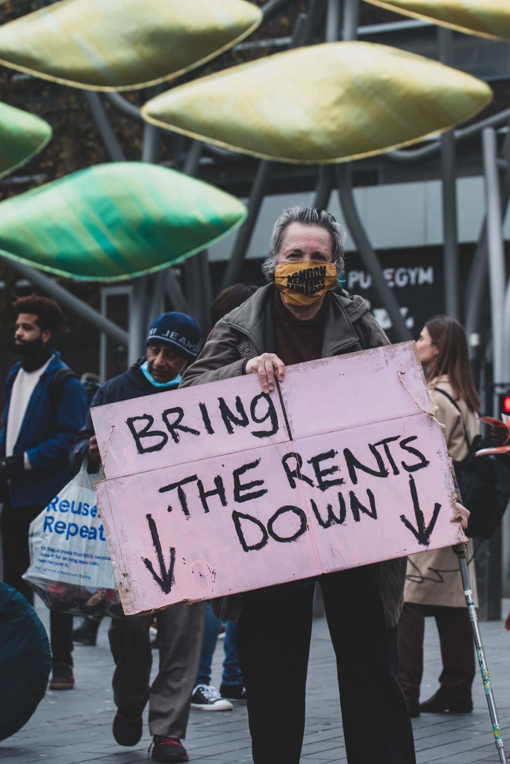 Man holding sign saying "bring the rents down" at a London protest