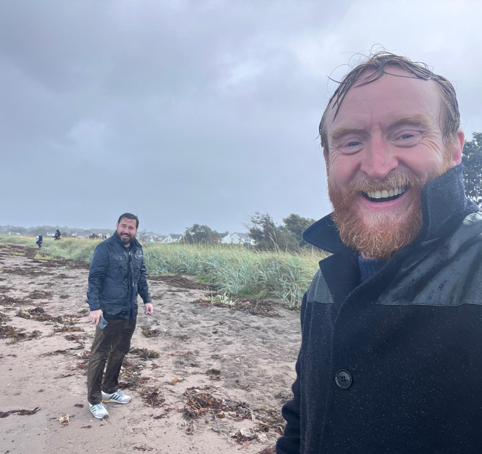 Martin Compston and Tony Curran, soaking wet, on a beach in Scotland filming  Mayflies
