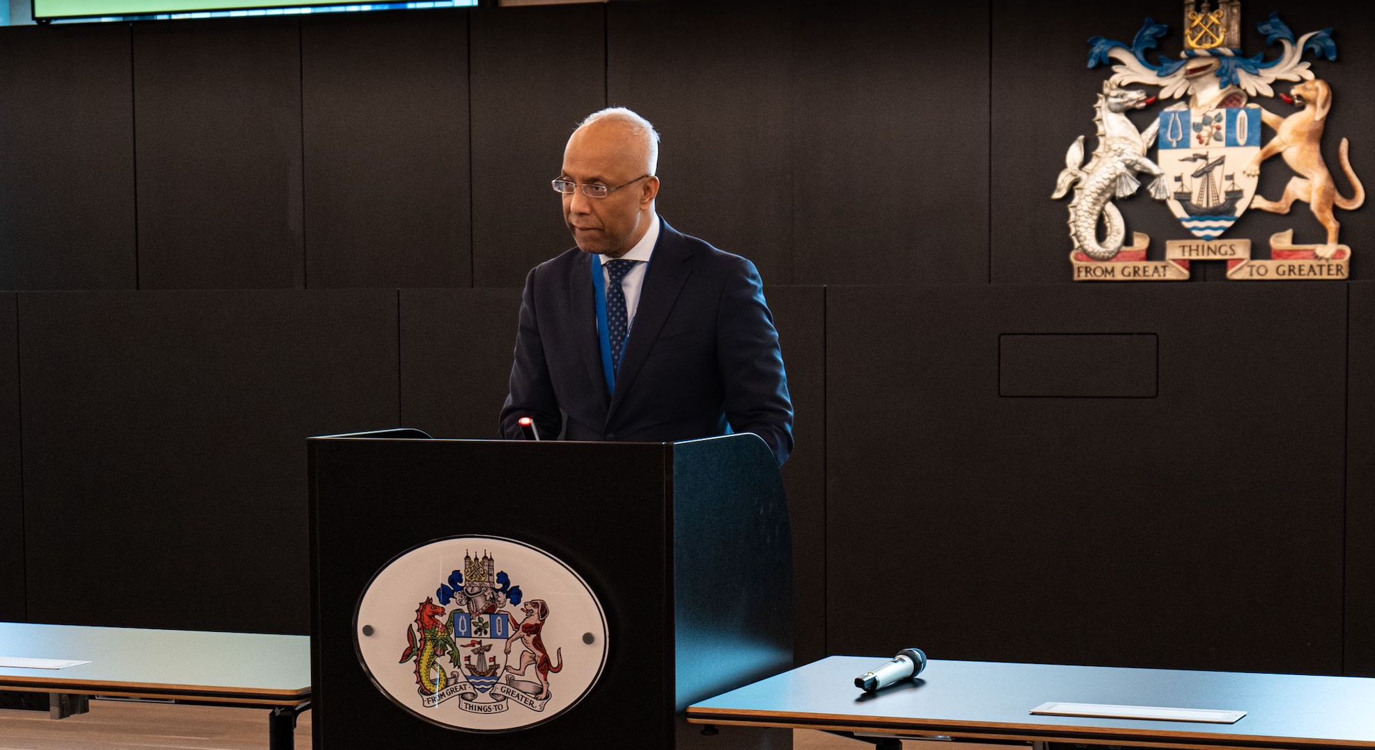 Mayor Luftur Rahman speaking at a lectern at the Tower Hamlets town hall