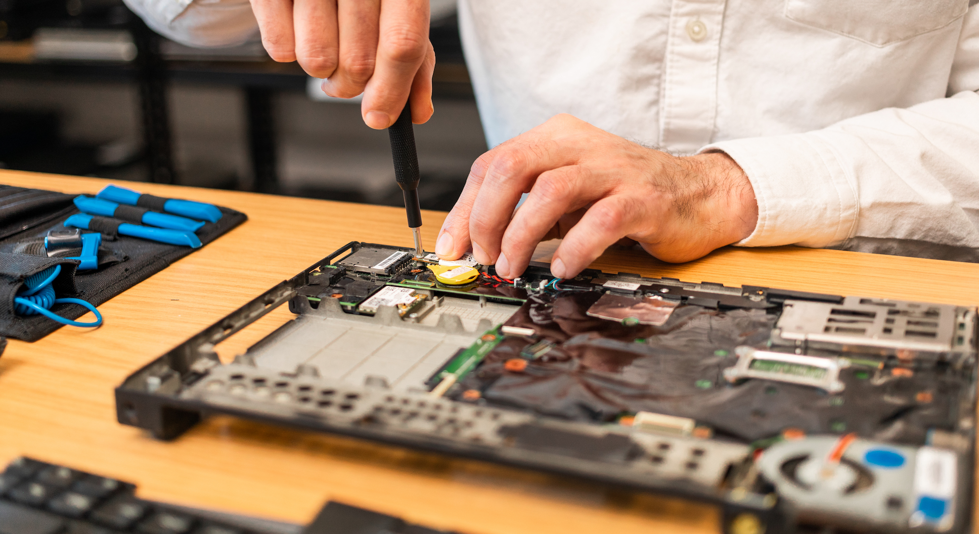 man fixing computer motherboard with screwdriver for Repair Week 2022