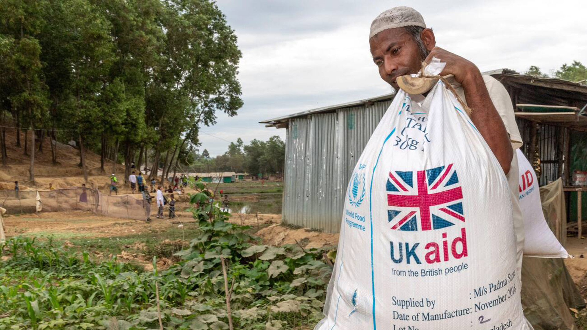 A Rohingya man carries a UK Aid bag in a refugee camp in Bangladesh