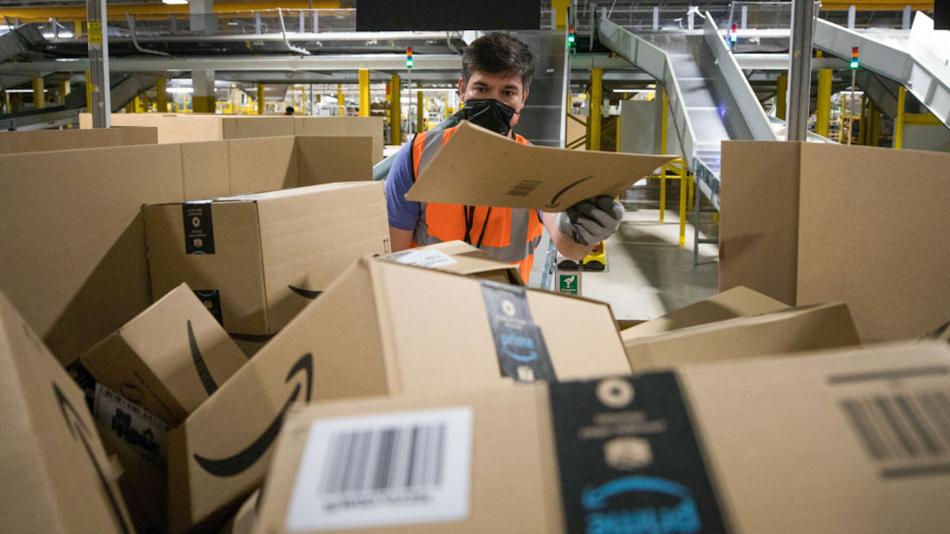 An employee places a package into a distribution box at an Amazon.com Inc. fulfilment center in Kegworth, U.K., on Monday, Oct. 12, 2020.