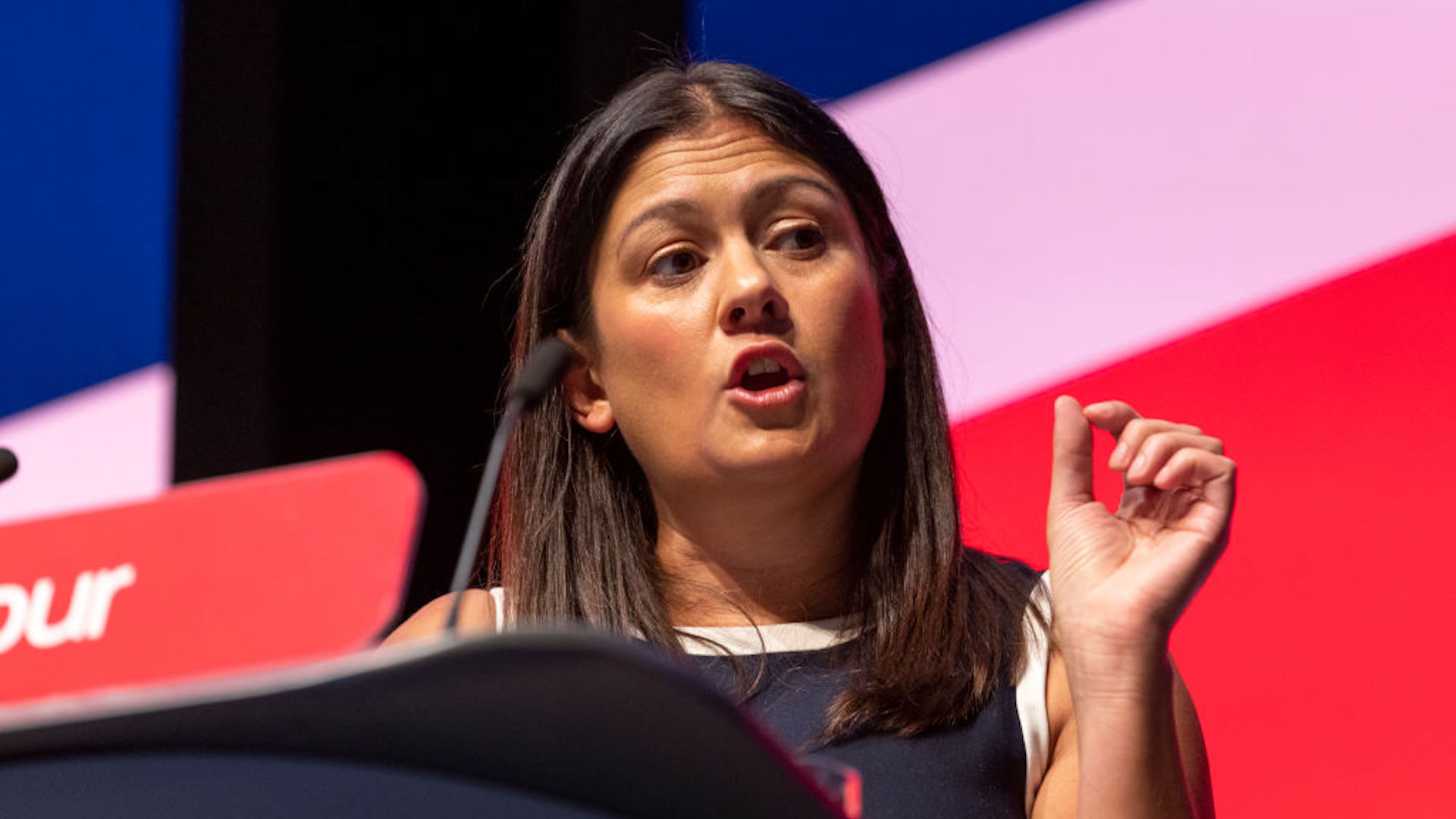 Lisa Nandy stands a t a lectern with Labour on the front and a union jack behind her