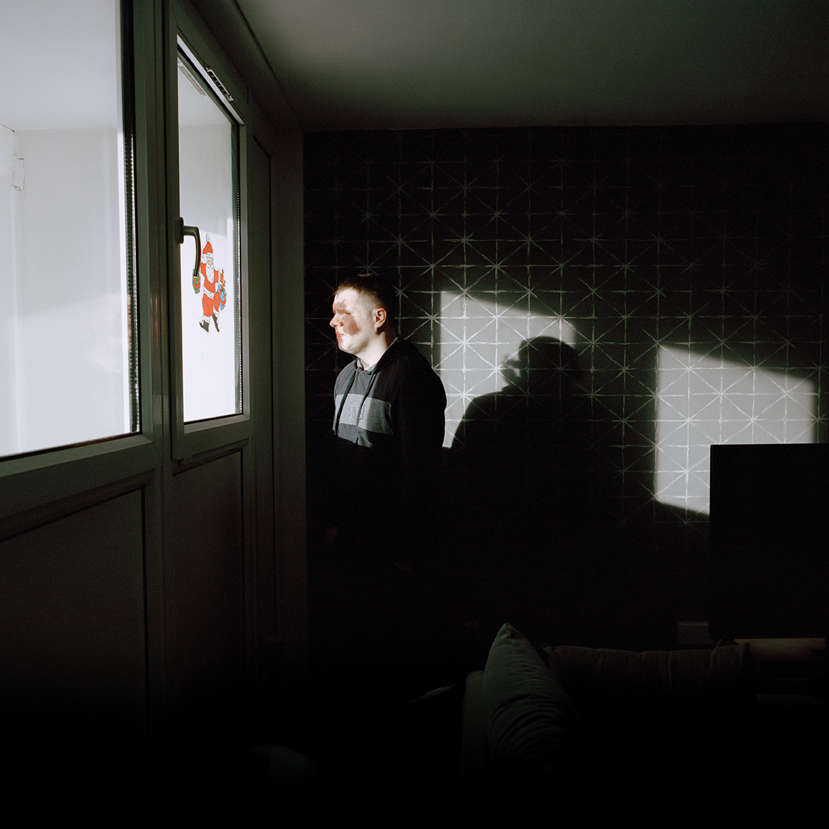 man looks out the window in shadow
