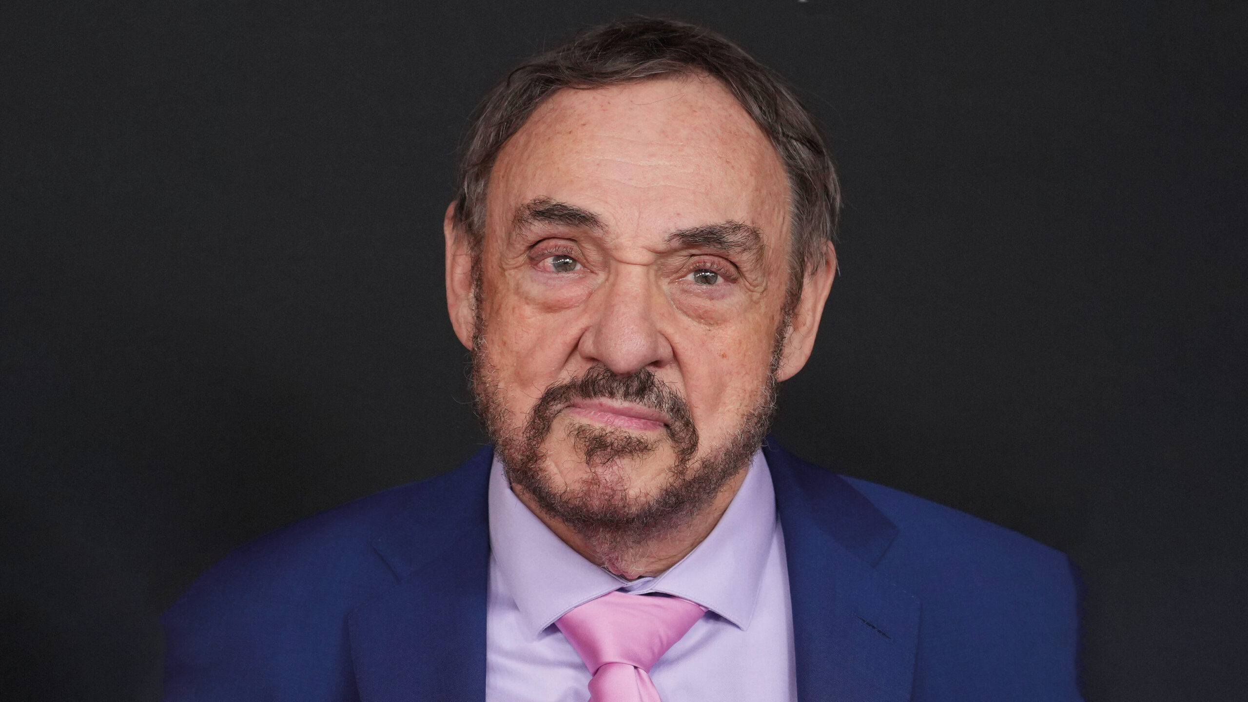John Rhys-Davies in a blue jacket and pink tie