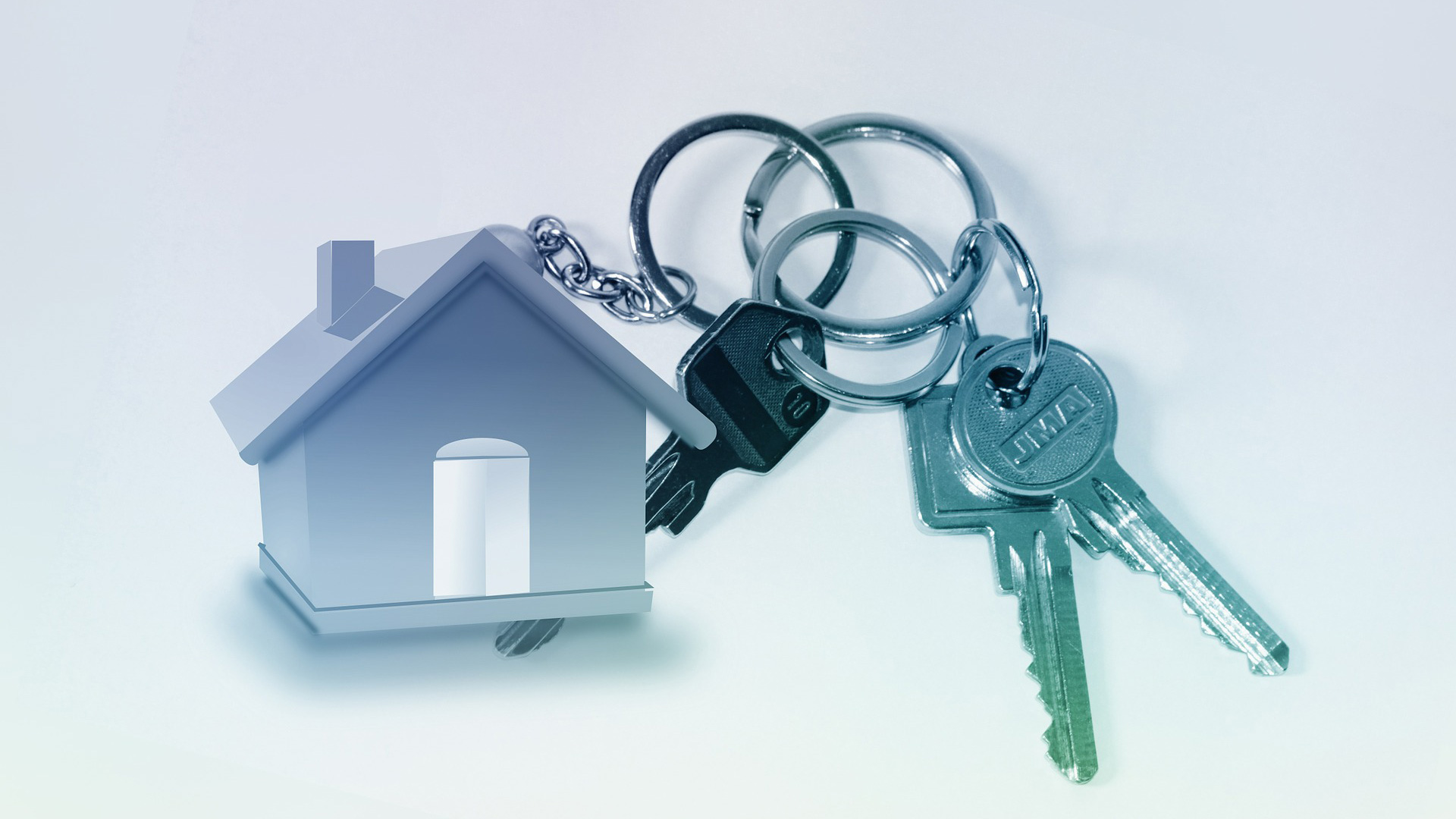 A model of a house and some keys, green and blue on a white background