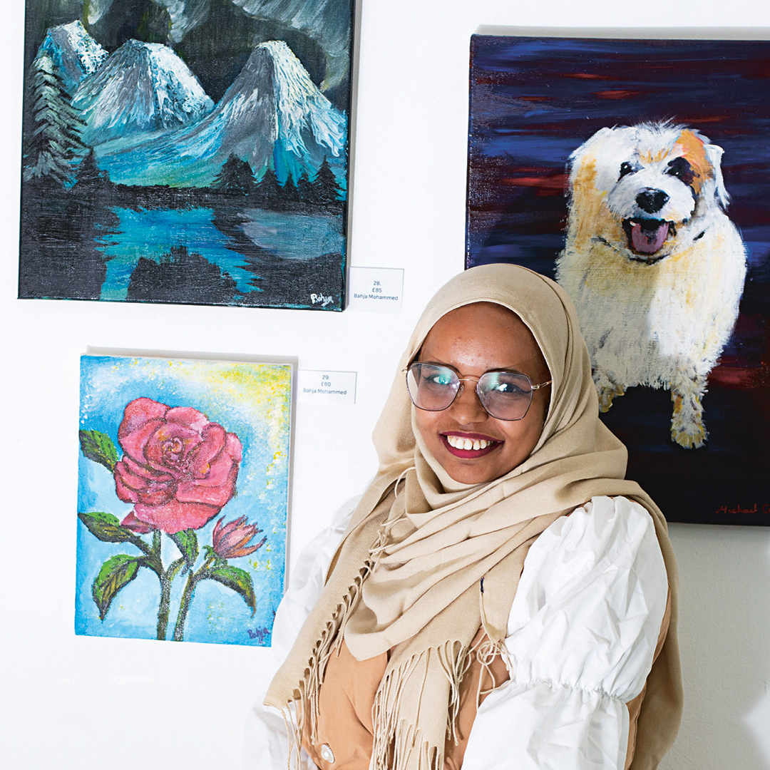 Bahja Mahamad beside paintings Pandora Garden and River Rose