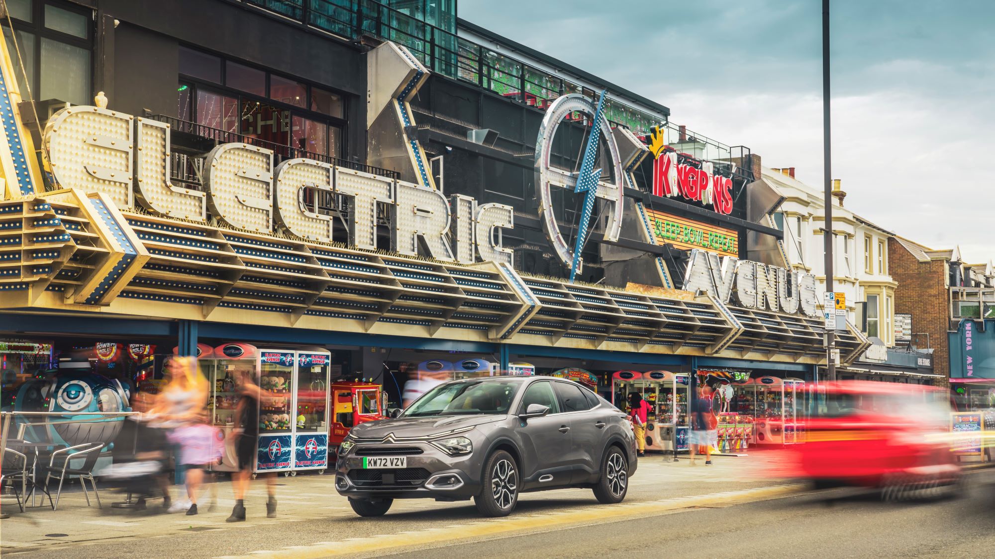 A grey Citroën ë-C4 X Electric drives past the Electric Avenue games arcade in Southend-on-Sea.