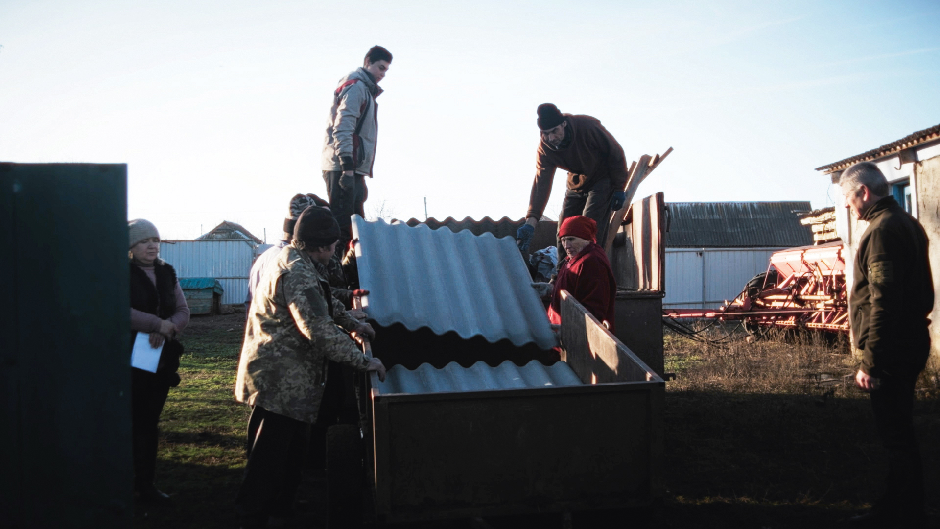 People unload corrugated iron from a truck