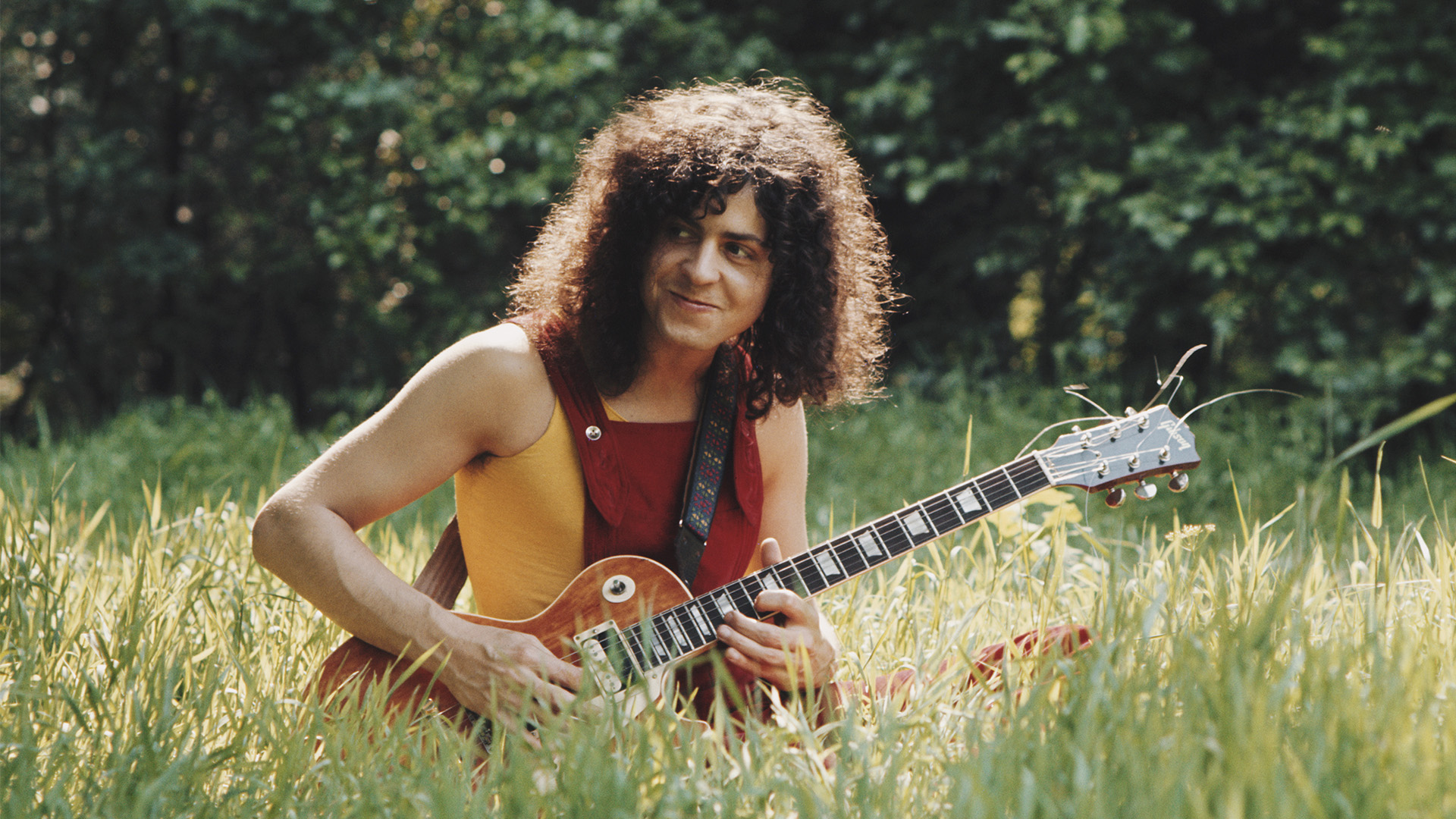 Marc Bolan playing guitar in a field
