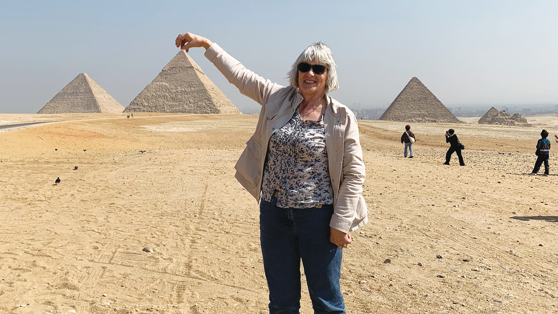 A woman poses beside pyramids